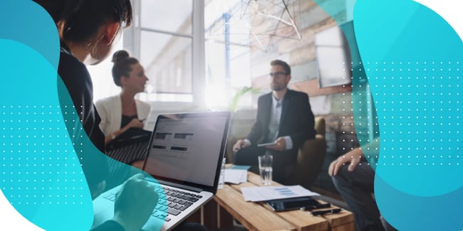 People in a meeting reviewing data on a laptop screen