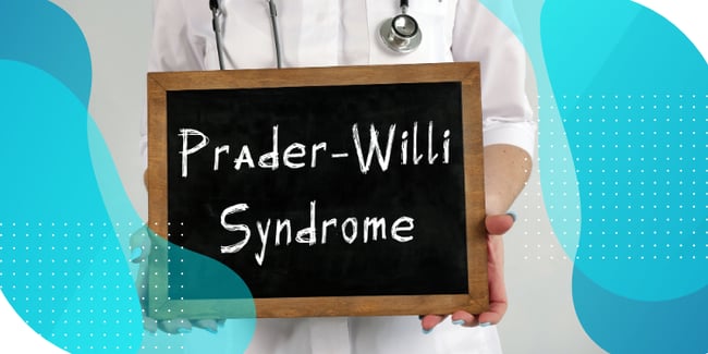 A doctor holding a chalkboard displaying the phrase 'Prader-Willi Syndrome'