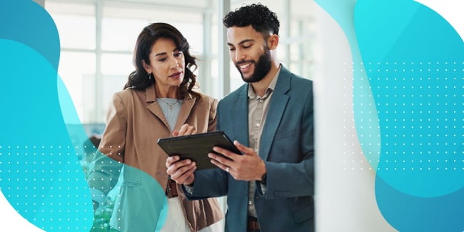 Two business professionals reviewing information on a tablet device in a modern office environment